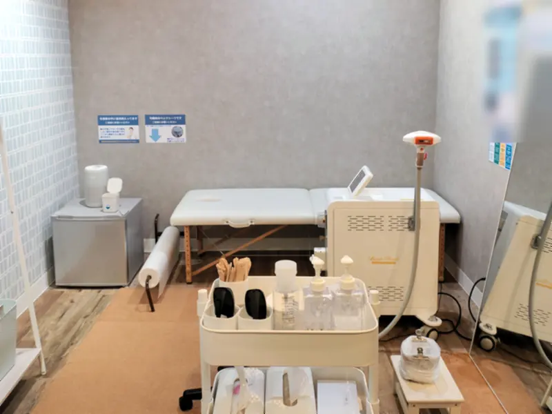 静岡鷹匠店の個室。ベッドと脱毛機、鏡がある室内